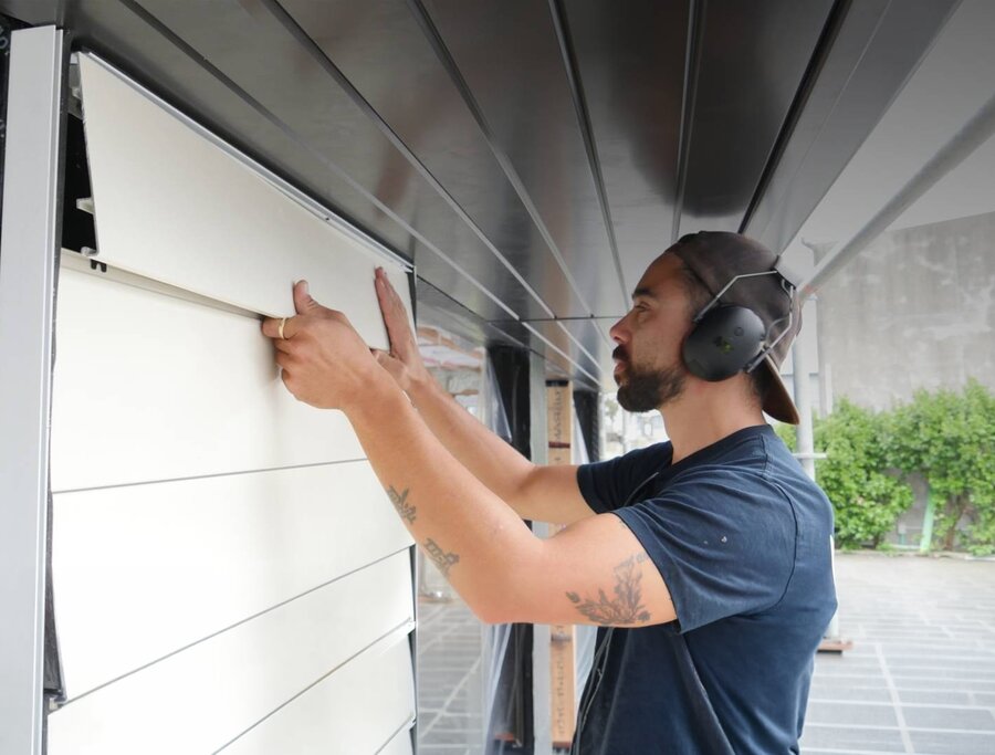 An installer wearing ear protection fitting an Eurowood aluminium weatherboard panel