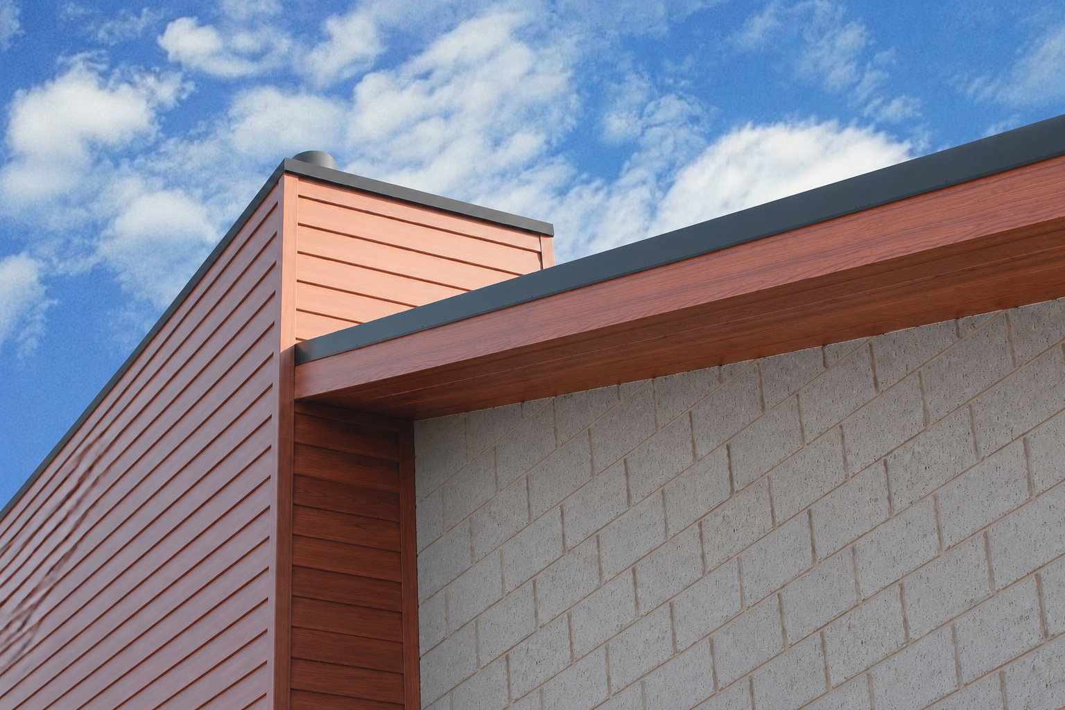 Wood-grain finish Eurowood aluminium weatherboard cladding on a building corner, against a blue sky