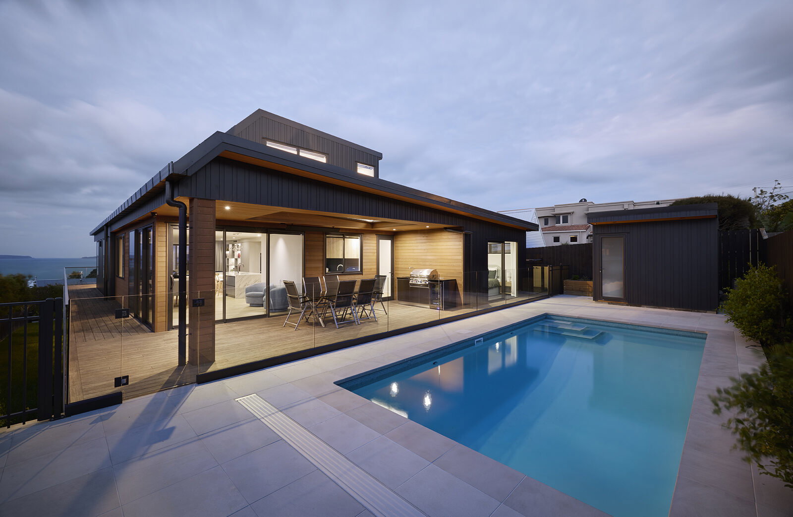 Evening view across the pool deck to the open-plan living and outdoor dining area
