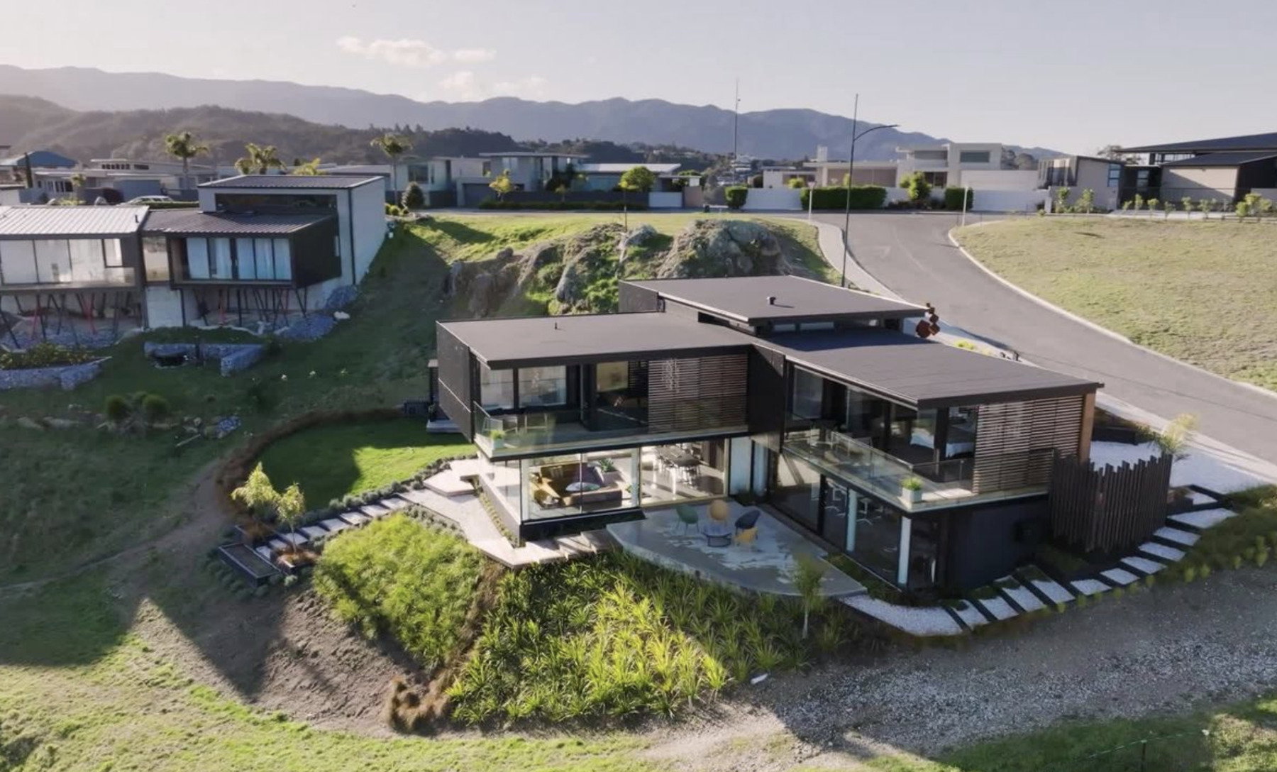 An aerial view of a modern home built into a coastal hillside