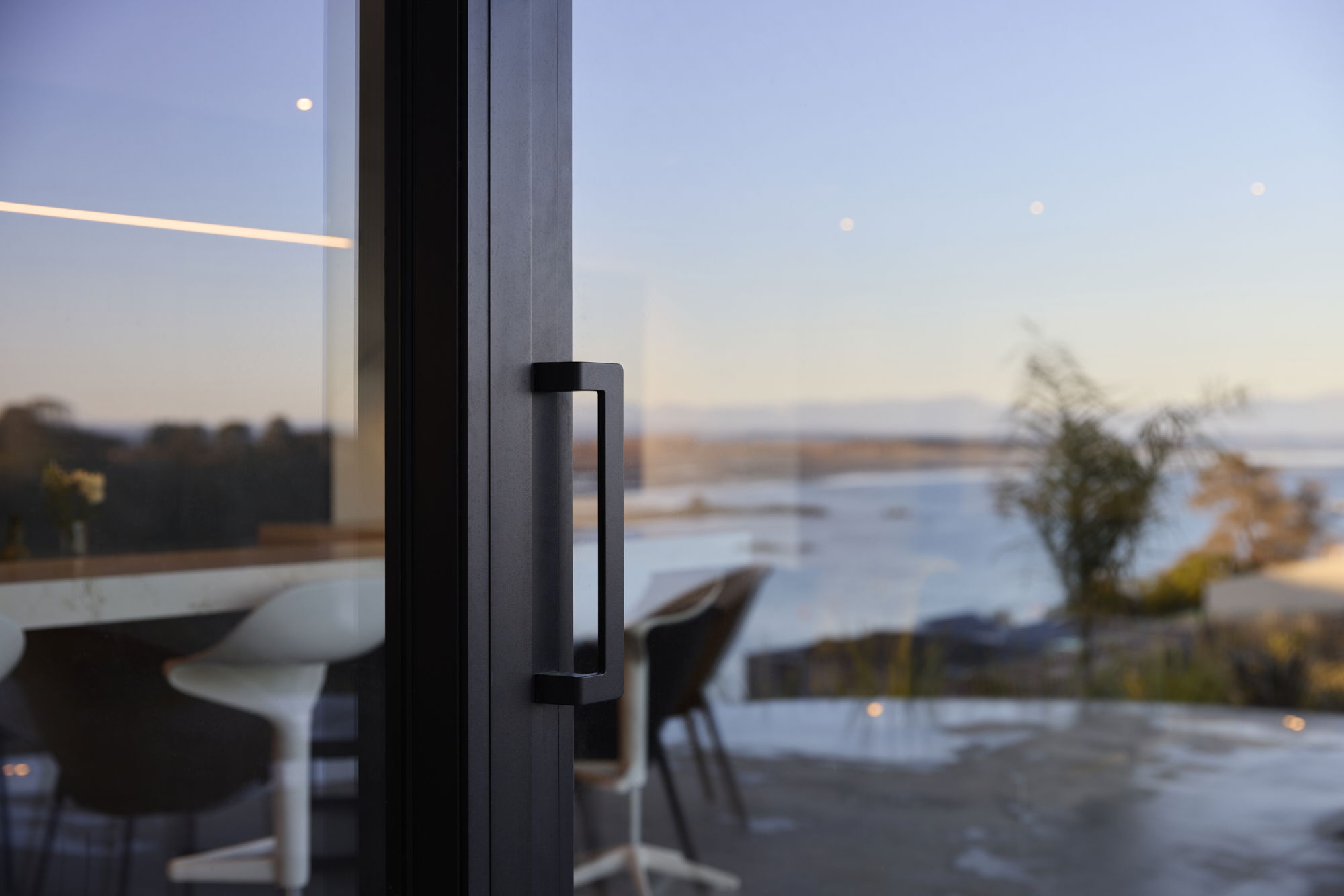 FMI Building Innovation hardware and accessories on a glass sliding door overlooking the coast