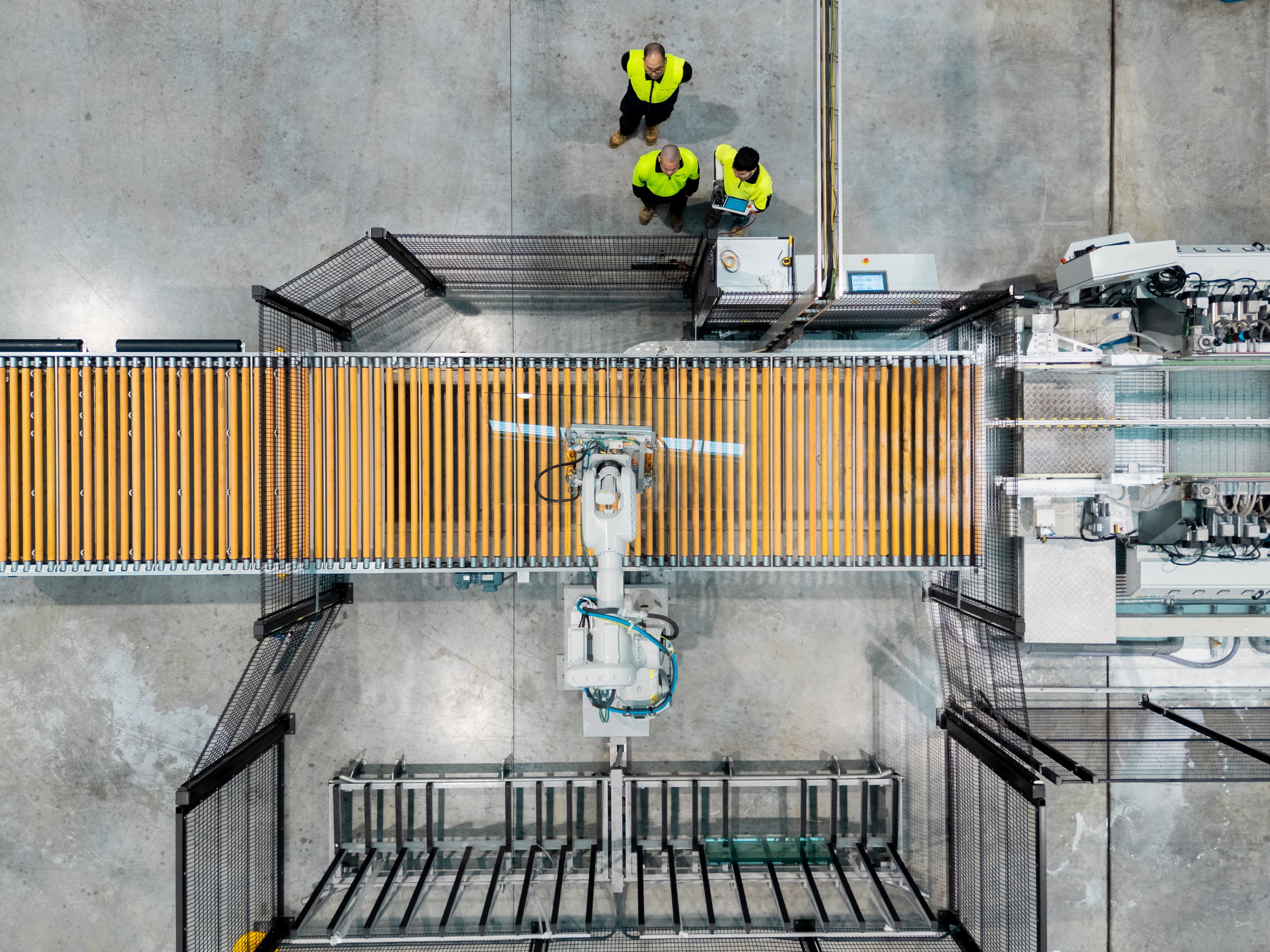 Top down view of an automated robotic arm picking up glass in a factory