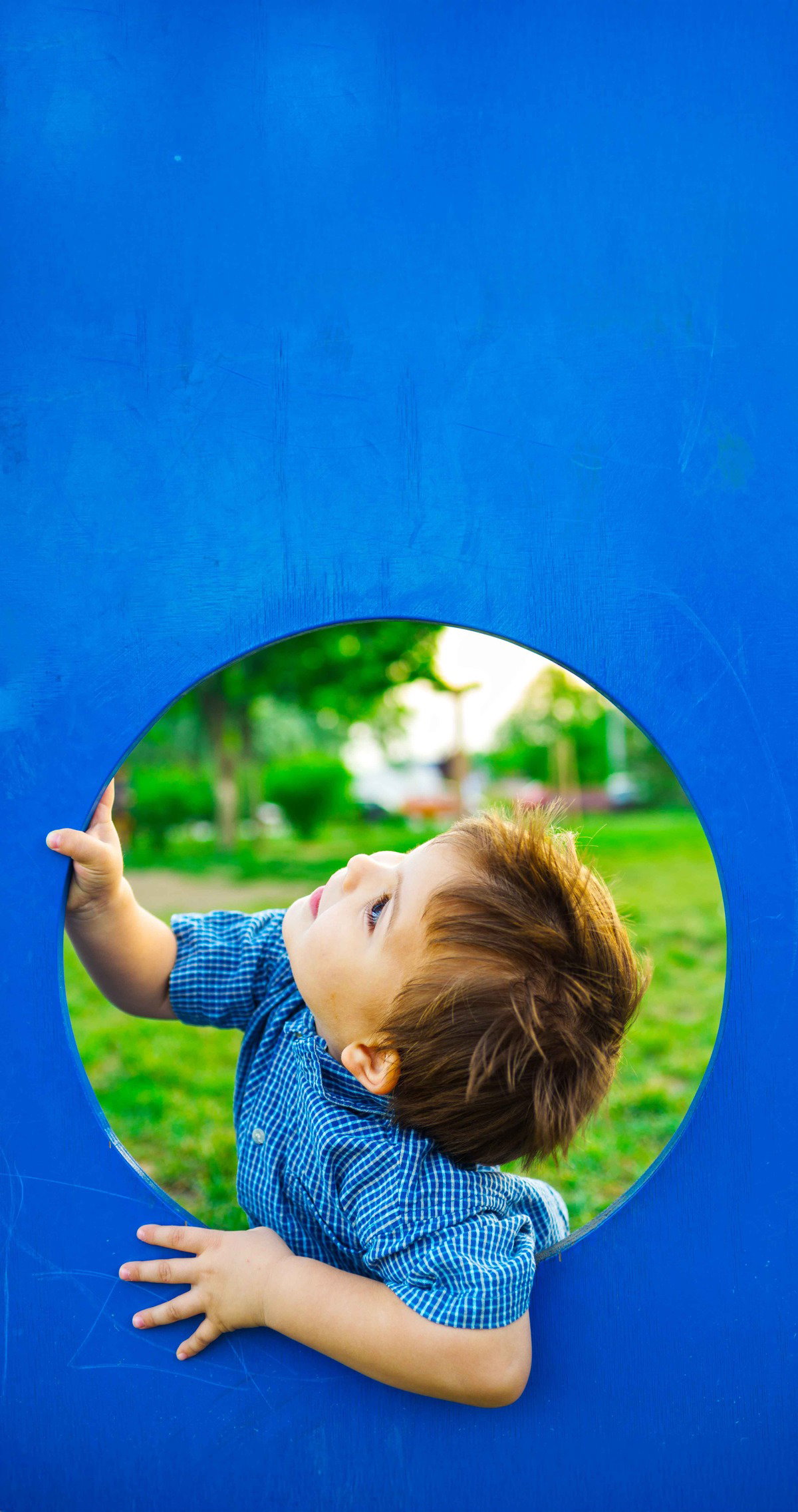 Image of a child peering through a circle in a playground